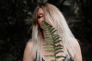 woman-standing-behind-fern-plant by .